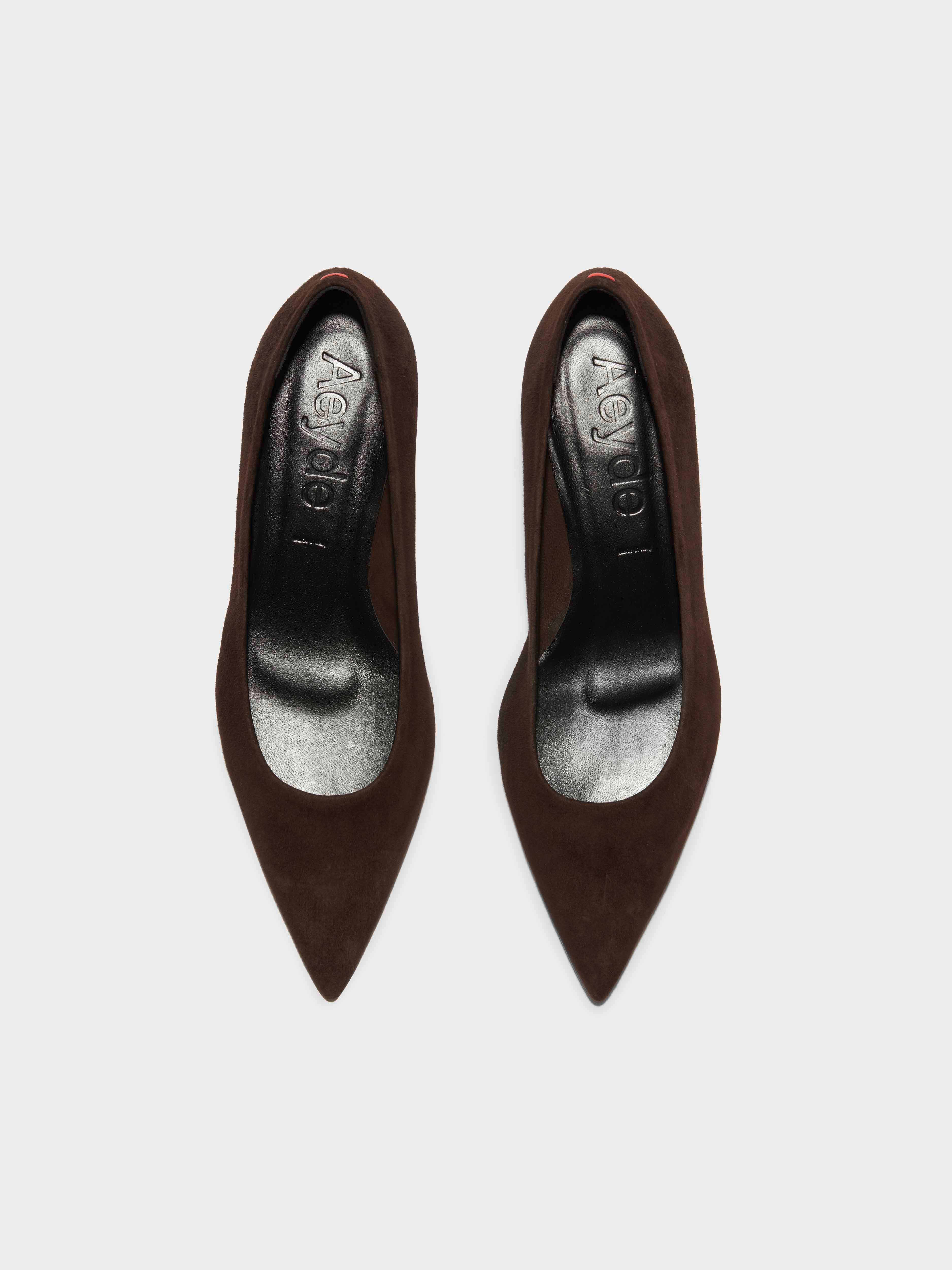 Mørkebrune, spidse pumps i ruskind set oppefra, med Aeyde logo indeni.