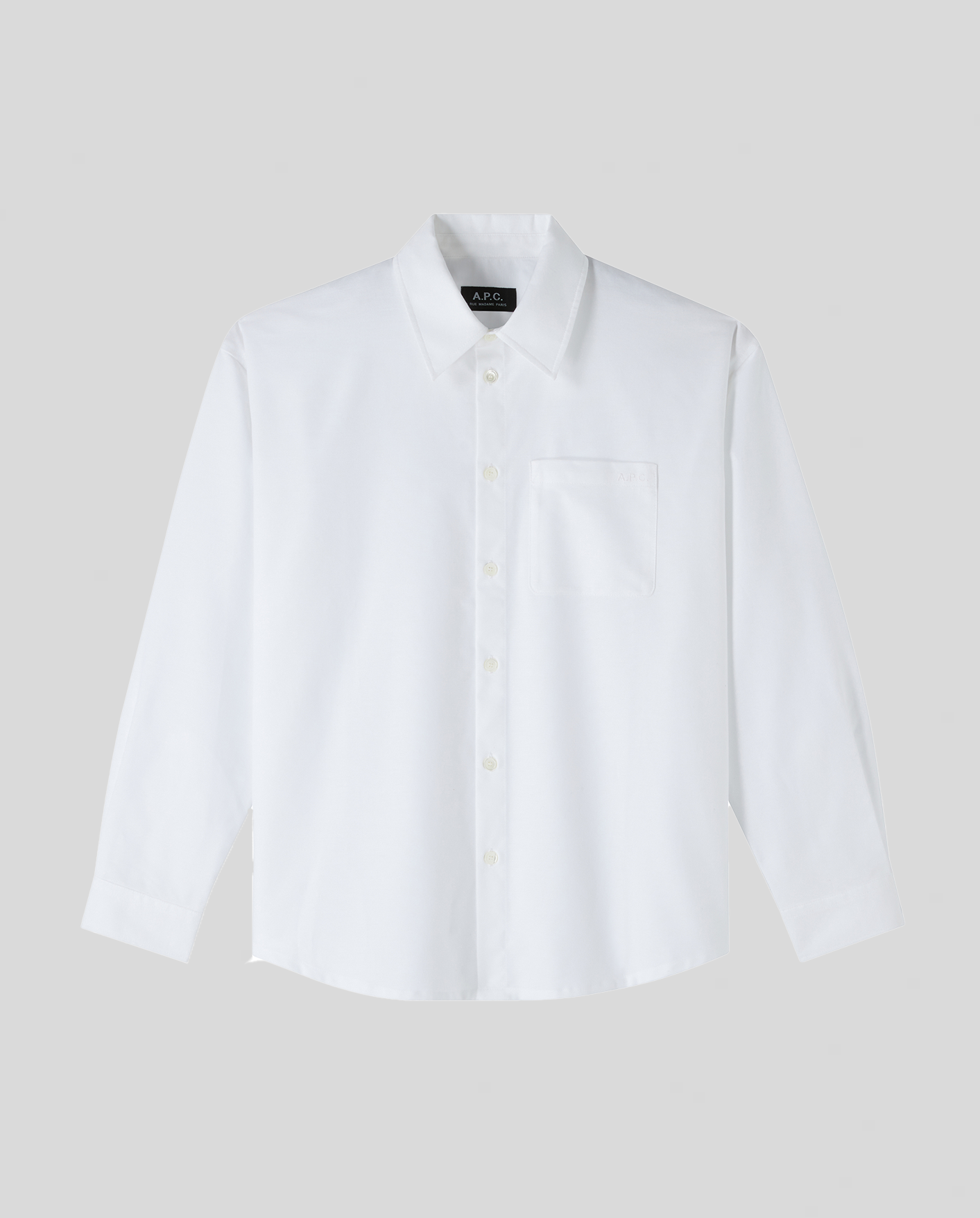 Hvid skjorte med lange ærmer, krave, venstre brystlomme og knaplukning foran.